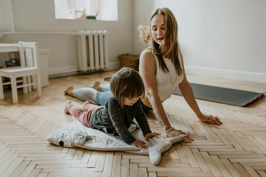 A woman teaches her young daughter a yoga pose