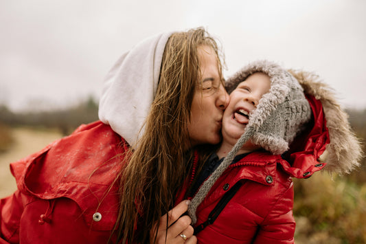 A mom playfully kisses her child as he laughs